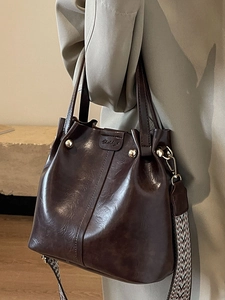 Retro dark brown leather bucket bag with metallic buckle and geometric woven strap