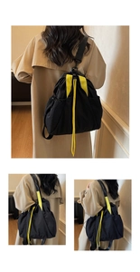 Detail of minimalist black drawstring backpack featuring vibrant yellow handles and straps