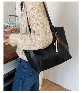 Détail d'un sac cabas noir tissé avec un pendentif décoratif en perles colorées