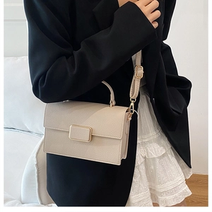 Detail of cream crossbody bag with lychee texture and matte gold clasp on a model