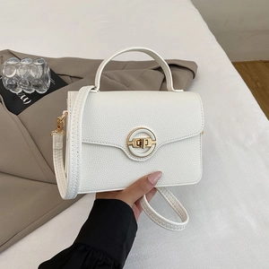 Détail du sac blanc à motif litchi avec un fermoir rond doré décoratif