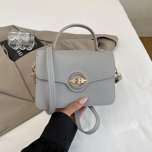 Détail du sac à main gris en cuir grainé avec fermoir rotatif doré et bandoulière chic