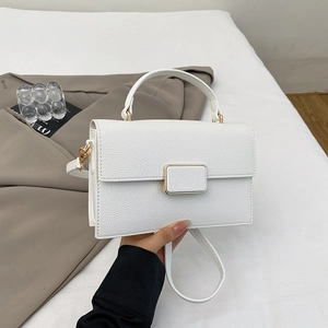 Close-up of white lychee pattern leather handbag with elegant gold square metal buckle