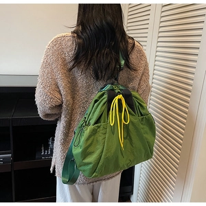 Rear view of a green canvas drawstring bucket backpack with yellow cord and large side pocket