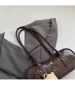 Detail view of deep brown glossy leather Boston bag with a cute plush bear pendant accessory