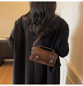 Close-up of a brown suede Boston bag styled on a black blazer for a retro autumn look
