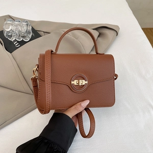 Détail du sac à main marron foncé en cuir grainé avec fermoir métallique circulaire