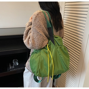 Side view of large green nylon tote bag featuring adjustable yellow drawstrings