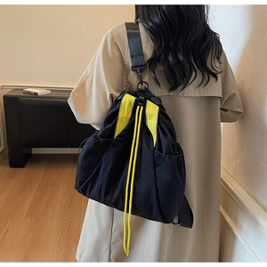 Rear view of model wearing a black nylon drawstring backpack with bright yellow accents
