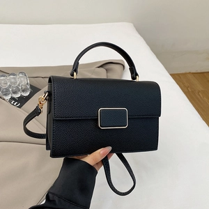 Detail of black lychee texture leather handbag with gold buckle and top handle