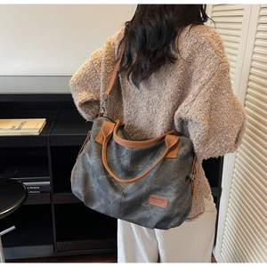 Detail of vintage grey canvas tote bag with brown straps and leather logo patch
