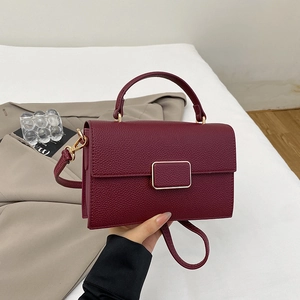 Close-up of wine red lychee pattern leather handbag with gold metal clasp buckle