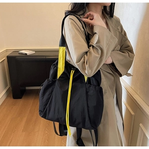 Detail of black nylon backpack with bright yellow straps and drawstring for urban leisure
