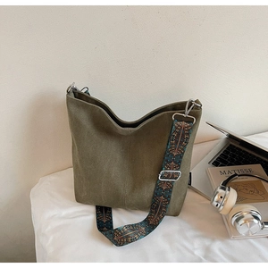 Olive green tote bag detail with colorful wide ethnic pattern shoulder strap on desk