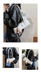 Detail of white Boston bag featuring a metallic logo and a cute brown bear charm