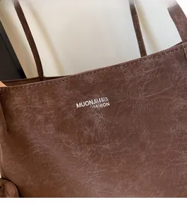 Detail view of dark brown tote bag showing retro textured leather and branded logo