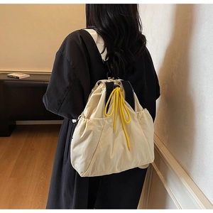 Detail view of cream drawstring backpack with yellow contrast cords on model's back