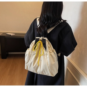 Detail view of cream canvas drawstring backpack with contrast yellow cords and black straps
