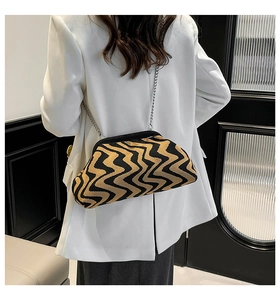 Detail of wavy knit crossbody bag with silver chain strap shown on white blazer