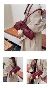 Detail of dark red leather Boston bag with plush bear charm and gold lettering