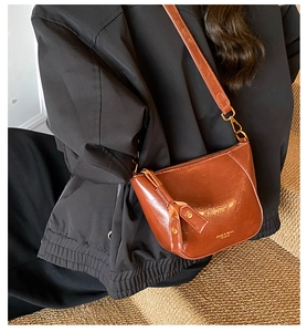 Brown half-moon crossbody bag in polished oil wax leather with adjustable shoulder strap