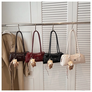 Detailed row of four shiny Boston bags in brown, burgundy, black, and cream finishes