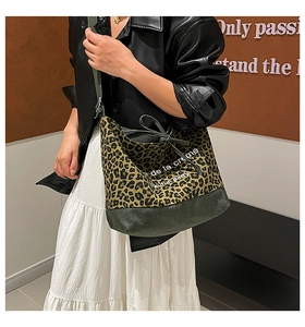 Detail of leopard print bucket bag with black leather base and green shoulder strap
