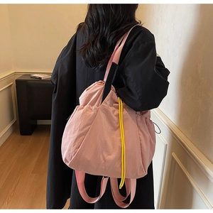 Detail of pink drawstring tote bag with yellow accents worn by model in minimalist room