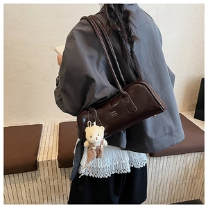 Detail of dark brown patent leather Boston bag with teddy bear charm and gold logo