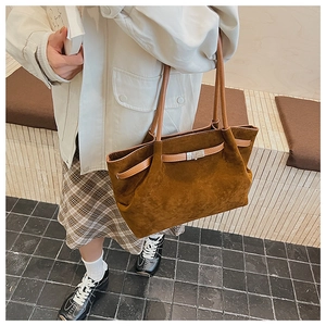 Detail of caramel suede bucket bag featuring silver twist lock and leather shoulder strap