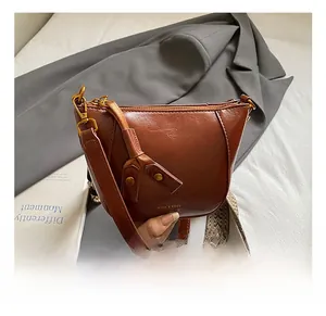 Detail view of brown vintage half-moon crossbody bag with bohemian patterned wide strap