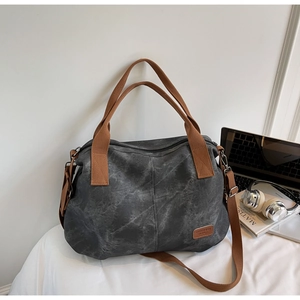 Detailed close-up of dark grey large canvas tote bag with brown woven handles and leather tag