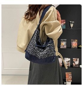 Detail of leopard print denim tote bag with printed letters on textured canvas fabric
