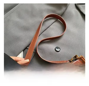 Close-up of the vintage bronze hardware and textured reddish-brown leather shoulder strap