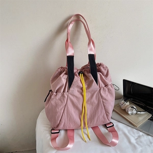 Pink nylon drawstring backpack with yellow cords and laptop for school use