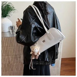 White minimalist Boston shoulder bag with plush bear charm shown on a female model