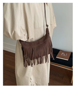 Close-up of brown fringe crossbody bag with knotted strap and suede texture detail