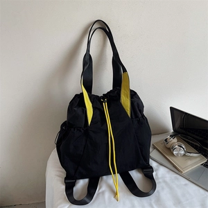 Detail showing the black nylon drawstring tote bag with contrasting yellow straps and buckles