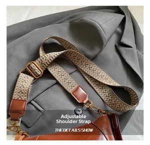 Detail of adjustable wide woven strap with retro gold metal buckle on a brown leather bag