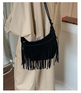 Detail of black suede tassel underarm bag with decorative fringe and knotted strap detail