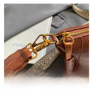Detail of a brown leather bag with golden metal hook and geometric woven strap pattern