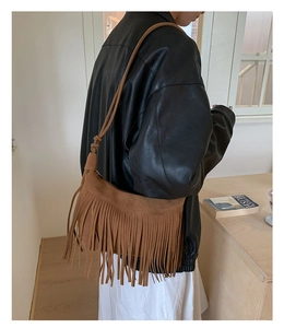 Detailed side view of a brown suede hobo bag with long fringes and slim shoulder strap