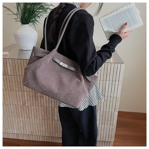 Detail view of large matte suede bucket bag with silver buckle on a female model