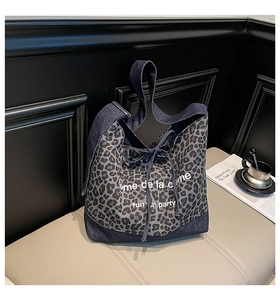 Detail of leopard print canvas tote bag featuring denim straps and cream text