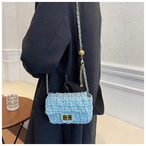 Close-up of light blue tweed shoulder bag with gold chain and adjustable metal ball