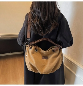 Detail of mustard yellow canvas tote bag with thick shoulder straps and metal eyelets