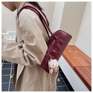 Burgundy Boston bag side view featuring gold logo and cute plush bear charm detail