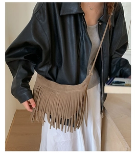 Detail of a brown fringe crossbody bag in soft suede finish shown on a model