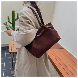 Detail of brown matte suede bucket bag with leather strap on a beige trench coat