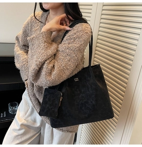Detail of black suede tote bag with matching coin purse pouch and gold lettering